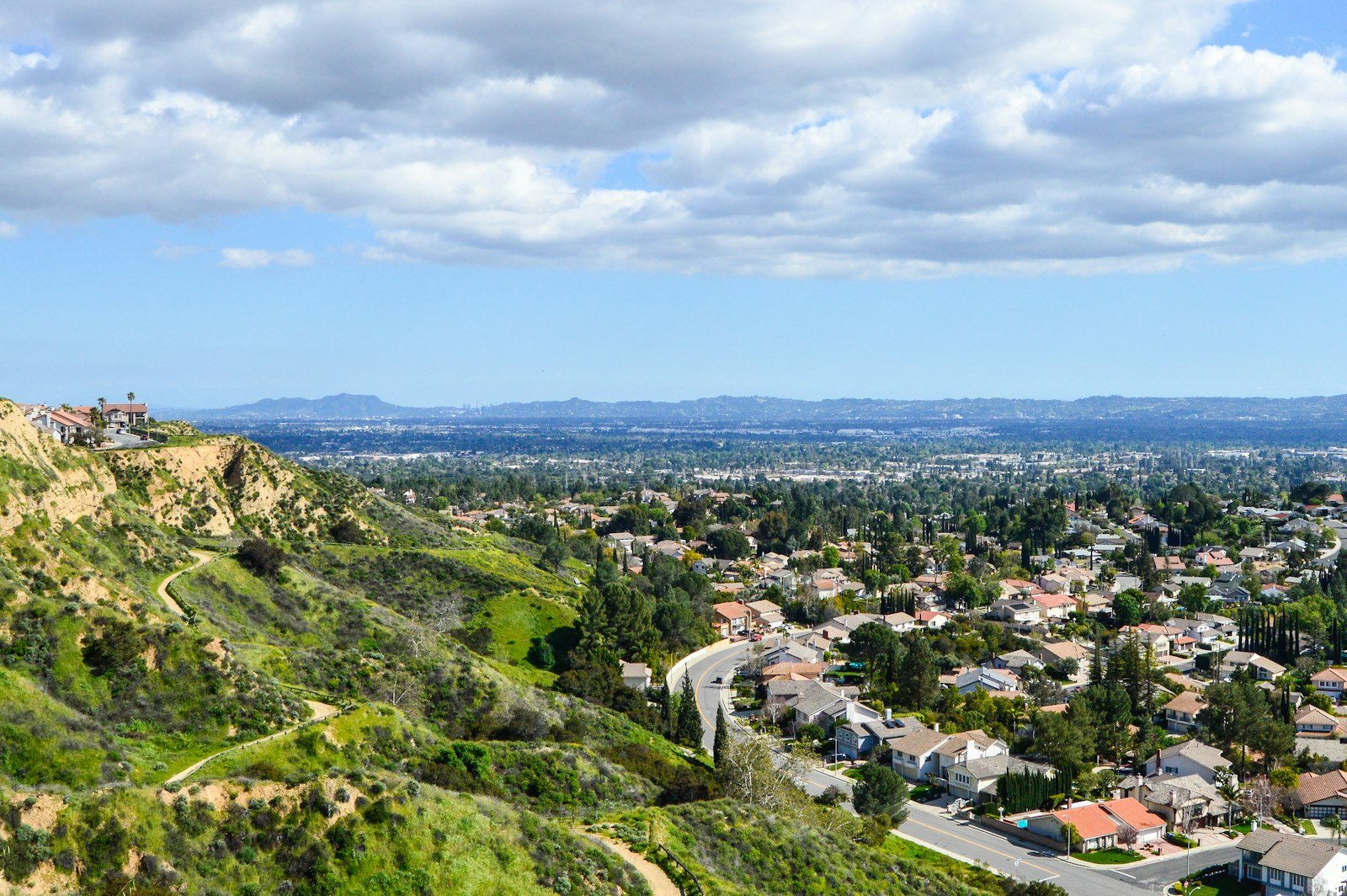 Green hills above the San Fernando Valley with homes and mountains in the distance